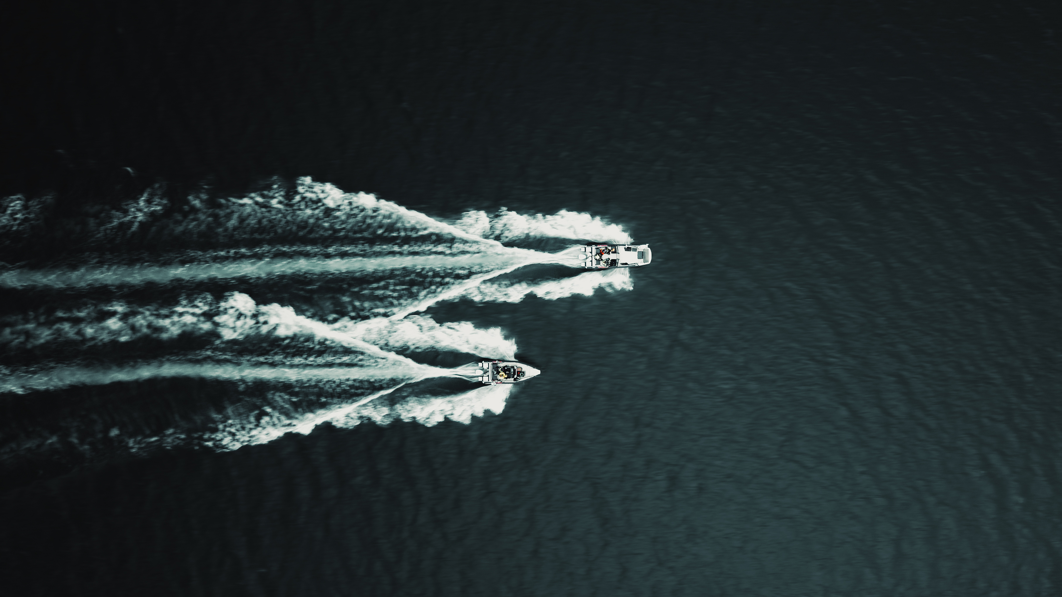 Yläilmoista kuvattu Faster 635 SC ja Faster 570 CC -alumiiniveneet, jotka ajavat vierekkäin. Ympärillä vain syvää, tummaa vettä.